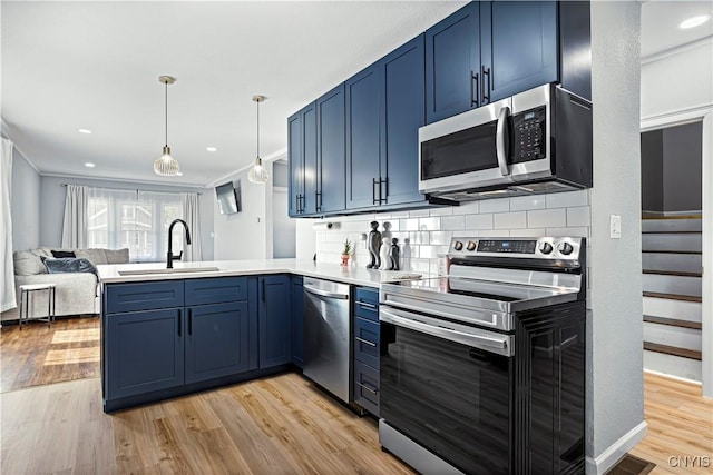 kitchen featuring kitchen peninsula, light wood-type flooring, stainless steel appliances, blue cabinets, and sink