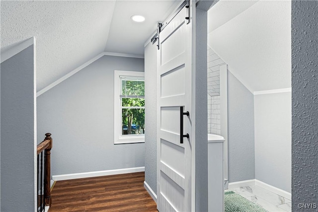 bonus room with a barn door, dark wood-type flooring, and vaulted ceiling