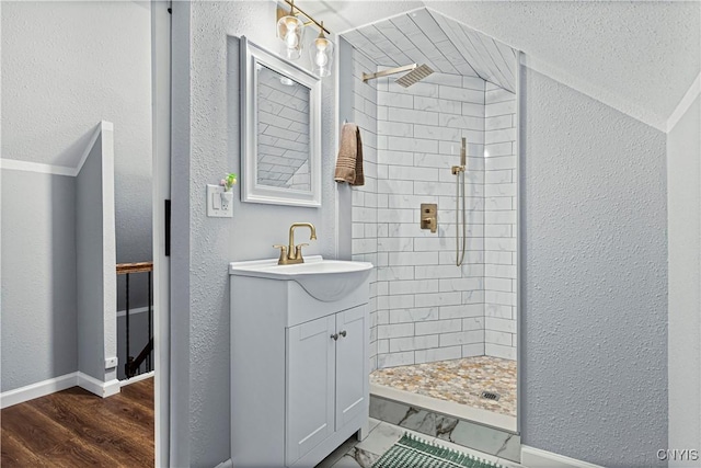 bathroom featuring vanity, wood-type flooring, and tiled shower