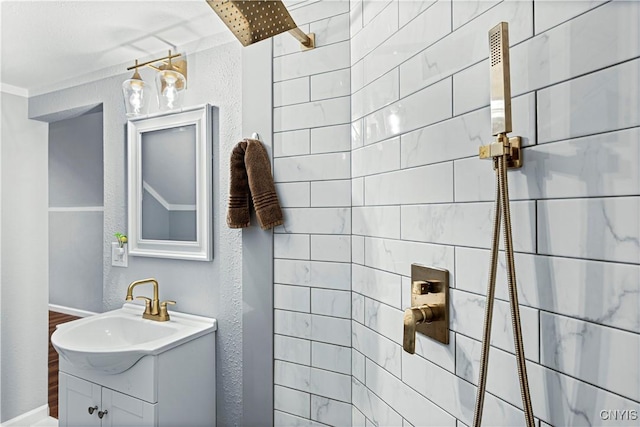 bathroom featuring vanity, crown molding, and tiled shower