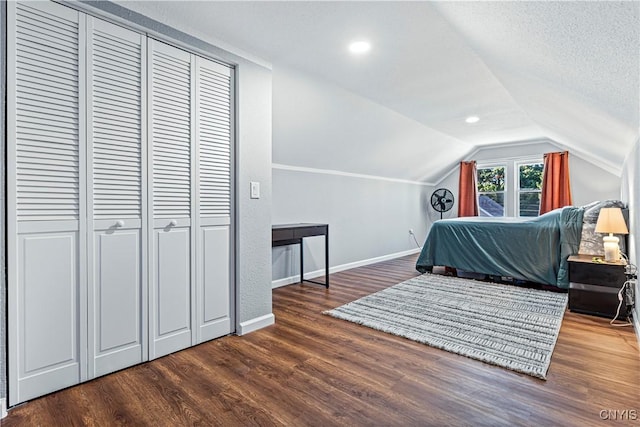 bedroom with dark hardwood / wood-style flooring, a textured ceiling, and vaulted ceiling