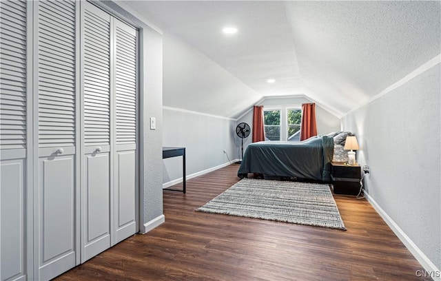 bedroom with a textured ceiling, dark wood-type flooring, and vaulted ceiling