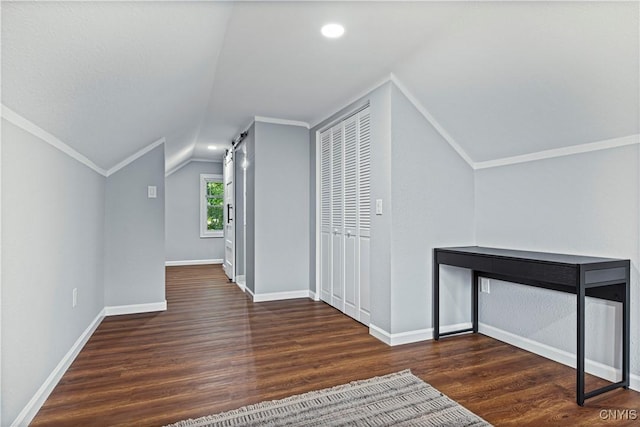 bonus room featuring a barn door, dark hardwood / wood-style flooring, and lofted ceiling