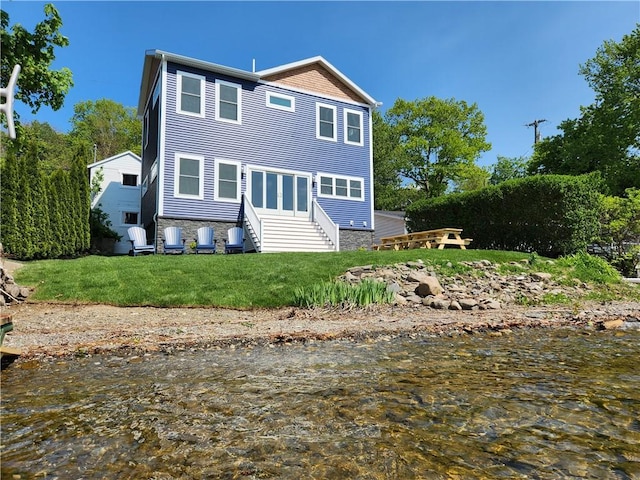 back of house with a water view and a lawn