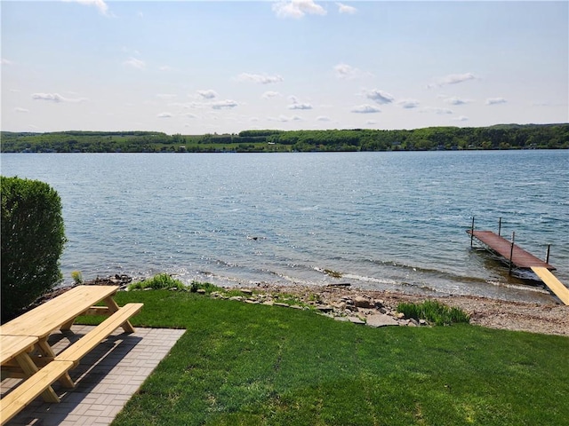 view of dock featuring a lawn and a water view