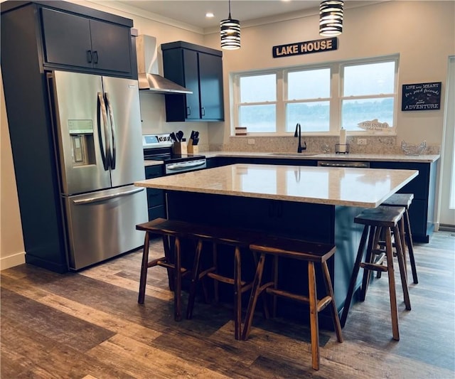 kitchen featuring a center island, wall chimney range hood, hanging light fixtures, dark hardwood / wood-style floors, and appliances with stainless steel finishes