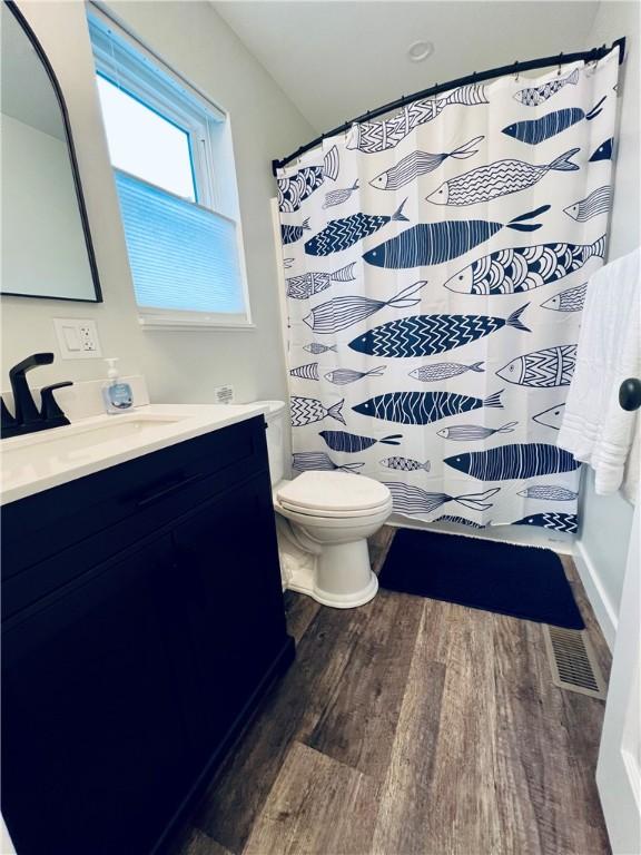 bathroom featuring curtained shower, vanity, wood-type flooring, and toilet