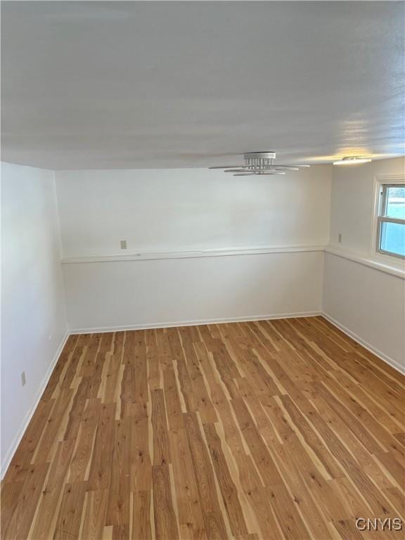 spare room featuring baseboards and light wood-style floors