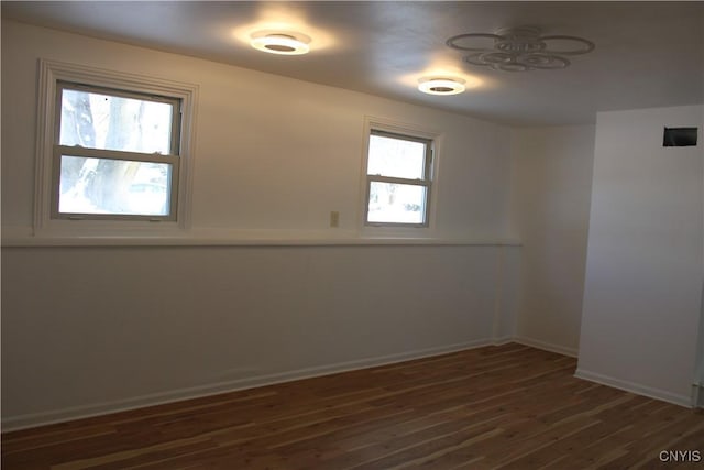 spare room featuring dark wood-style floors and baseboards