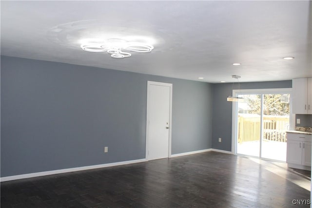 unfurnished living room with recessed lighting, a notable chandelier, dark wood-style flooring, and baseboards