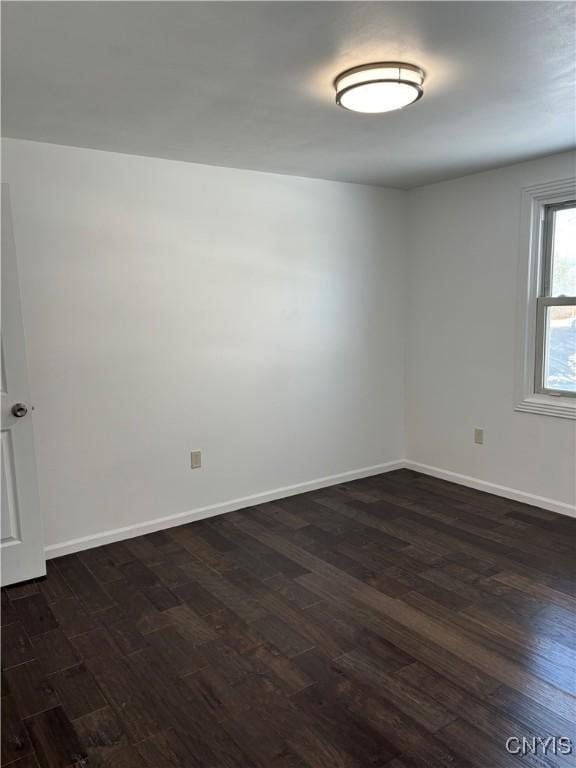 spare room featuring baseboards and dark wood-style flooring