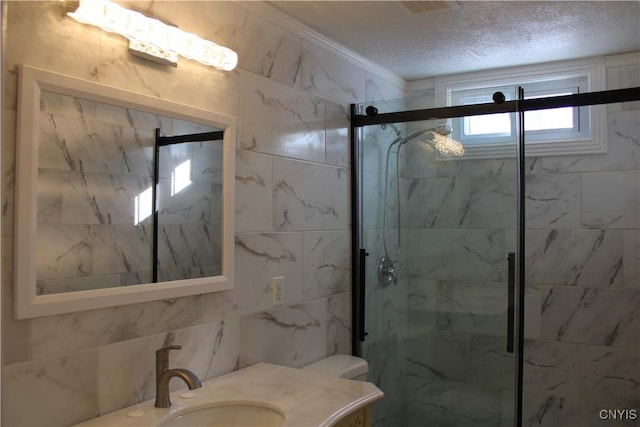 bathroom with a textured ceiling, vanity, a stall shower, and tile walls