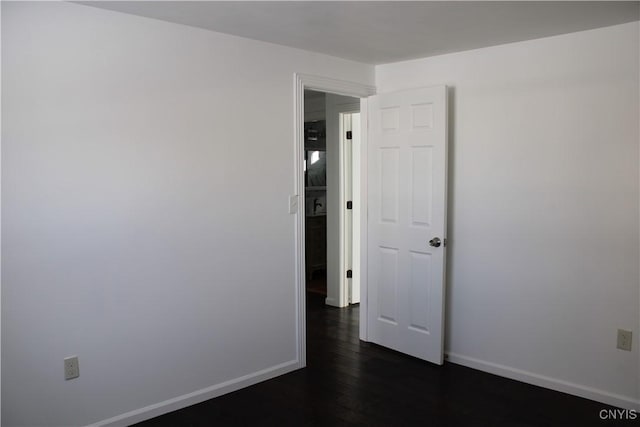 empty room featuring baseboards and dark wood-style flooring