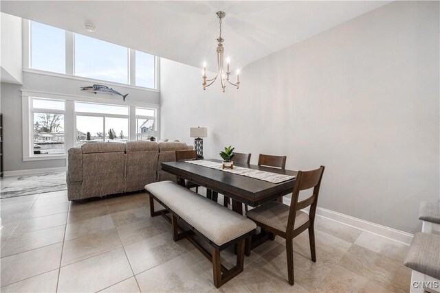 tiled dining area with a towering ceiling and an inviting chandelier