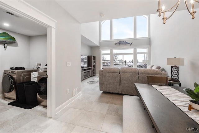 living room with a towering ceiling, a notable chandelier, and washer and clothes dryer