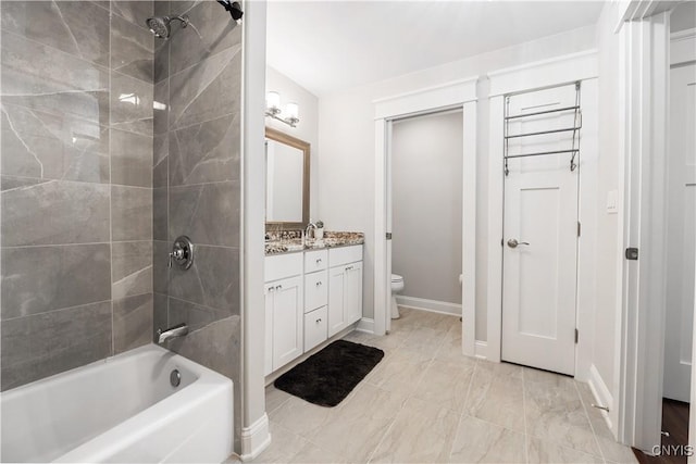 full bathroom featuring tiled shower / bath combo, vanity, and toilet