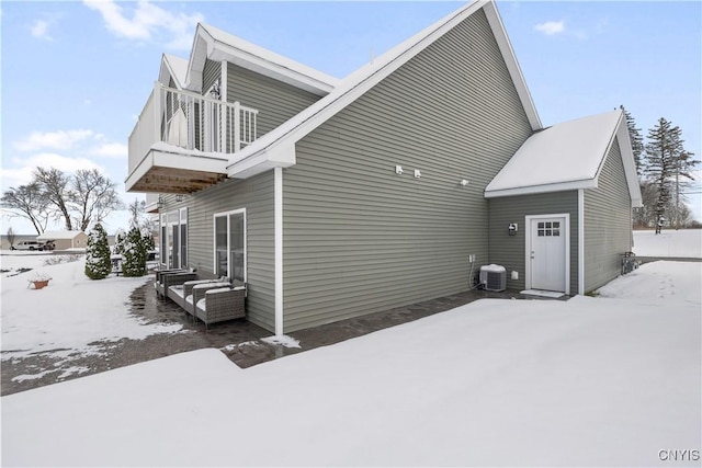 snow covered property with central AC and a balcony