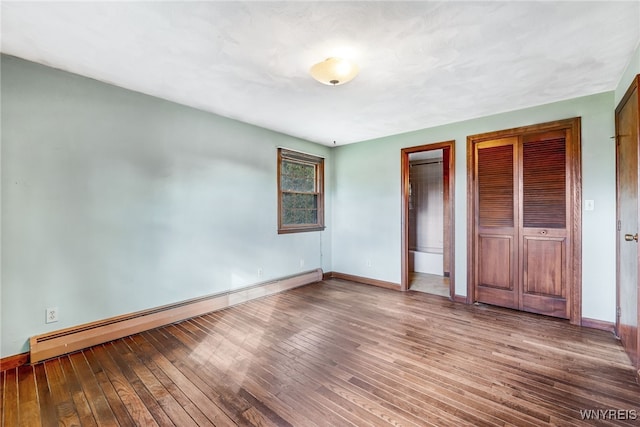 unfurnished bedroom featuring hardwood / wood-style floors and baseboard heating