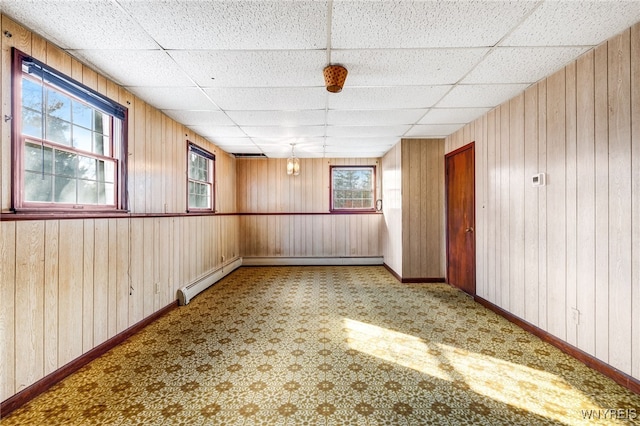 unfurnished room featuring a drop ceiling and wood walls