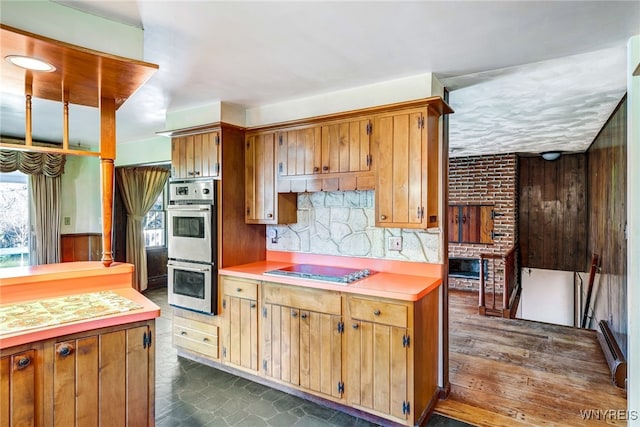 kitchen featuring tasteful backsplash, a brick fireplace, stainless steel appliances, wooden walls, and dark hardwood / wood-style floors