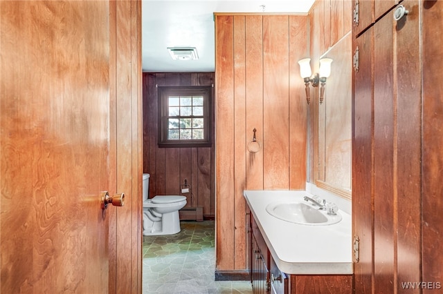 bathroom with wood walls, vanity, a baseboard radiator, and toilet