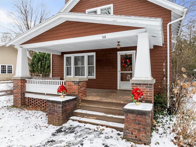 snow covered property entrance with a porch