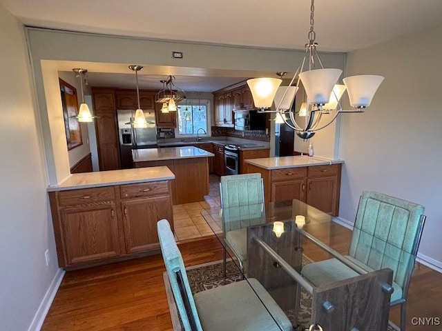 kitchen featuring pendant lighting, a kitchen island, wood-type flooring, and appliances with stainless steel finishes