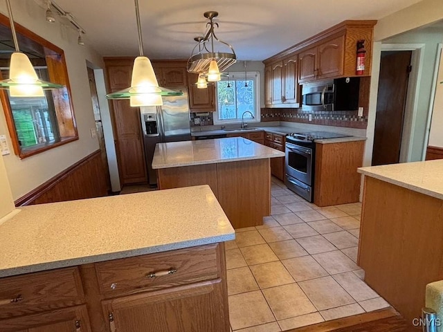 kitchen with pendant lighting, sink, decorative backsplash, appliances with stainless steel finishes, and a kitchen island