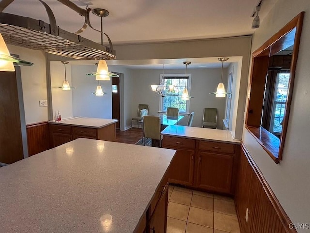 kitchen featuring a notable chandelier, wood walls, light tile patterned floors, decorative light fixtures, and a kitchen island