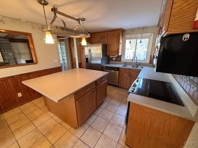 kitchen featuring appliances with stainless steel finishes, wood walls, a center island, hanging light fixtures, and light tile patterned flooring