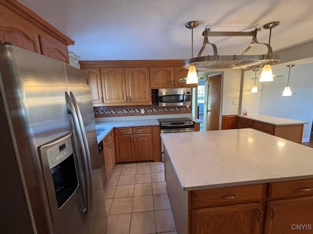 kitchen featuring tasteful backsplash, stainless steel appliances, light tile patterned floors, decorative light fixtures, and a center island