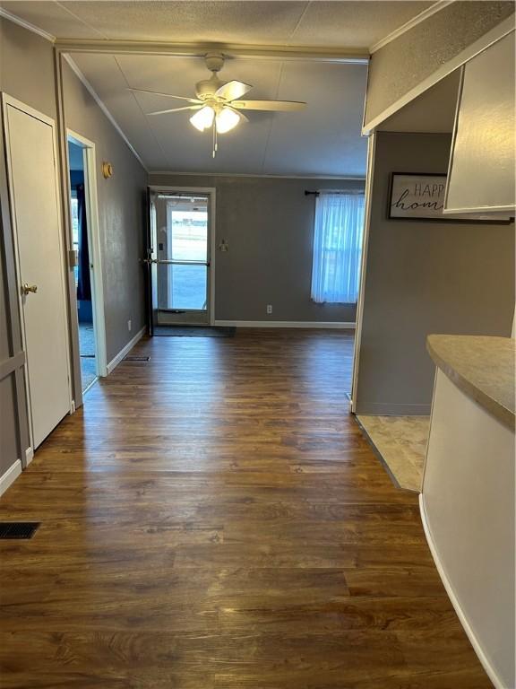 interior space with ceiling fan, dark hardwood / wood-style floors, and ornamental molding