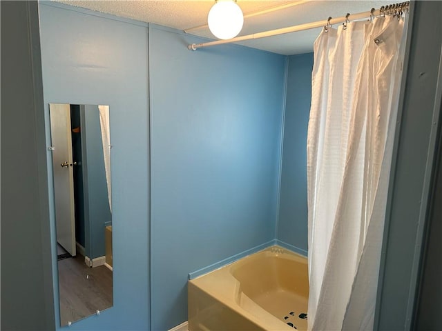 bathroom featuring hardwood / wood-style floors, a textured ceiling, and a tub to relax in