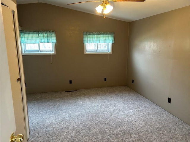 empty room featuring ceiling fan, carpet floors, a healthy amount of sunlight, and vaulted ceiling