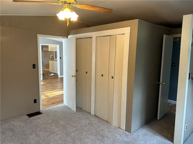 unfurnished bedroom with hardwood / wood-style floors, ceiling fan, and multiple closets