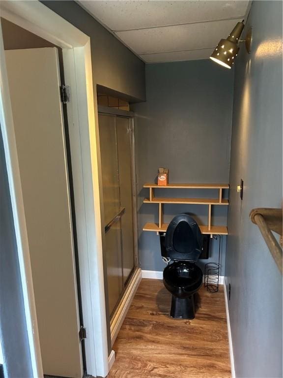 bathroom featuring toilet, a shower with door, and hardwood / wood-style flooring