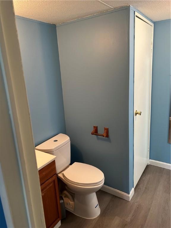 bathroom featuring hardwood / wood-style floors, vanity, a textured ceiling, and toilet