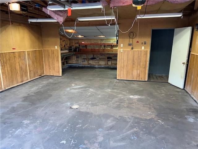 garage featuring a workshop area, a garage door opener, and wooden walls