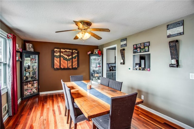 dining area with a textured ceiling, ceiling fan, and dark wood-type flooring