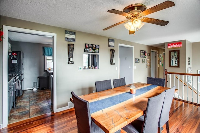 dining space featuring ceiling fan, dark wood-type flooring, and a textured ceiling