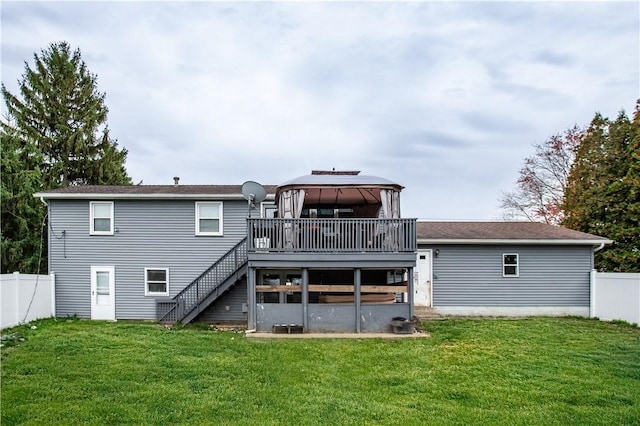 back of property featuring a gazebo, a wooden deck, and a lawn