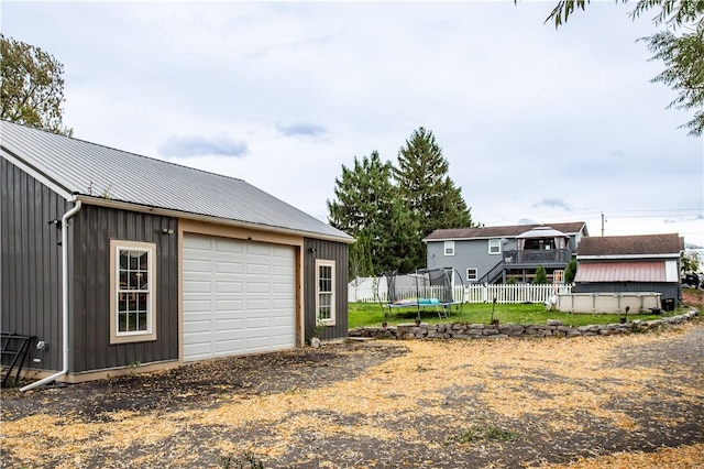 exterior space featuring a garage, an outdoor structure, and a trampoline