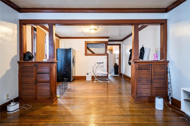 interior space featuring wood-type flooring, crown molding, and decorative columns