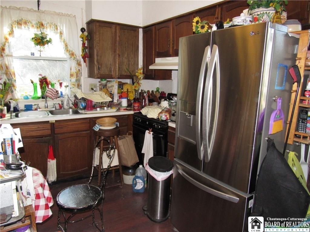 kitchen with dark brown cabinetry, sink, dark hardwood / wood-style flooring, stainless steel fridge, and black range with gas cooktop