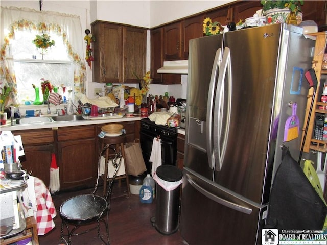 kitchen with dark brown cabinetry, sink, dark hardwood / wood-style flooring, stainless steel fridge, and black range with gas cooktop