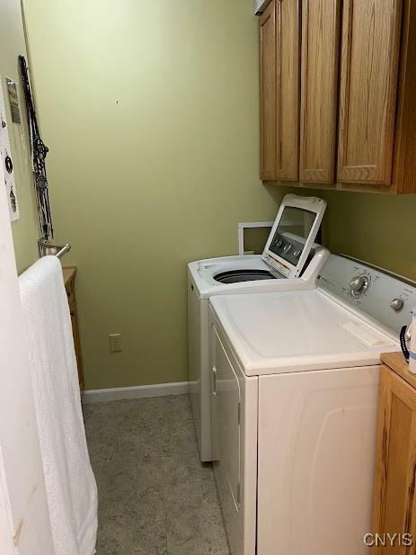 clothes washing area featuring washing machine and dryer and cabinets