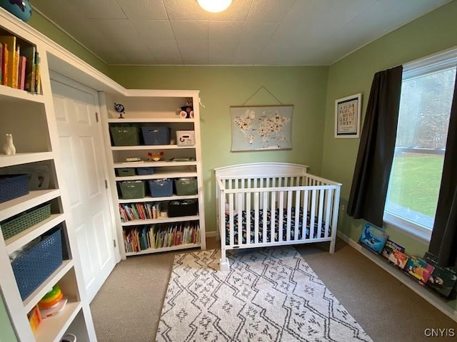 bedroom featuring carpet flooring, a crib, and multiple windows