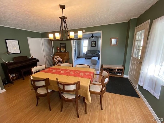 dining room with ceiling fan with notable chandelier, a textured ceiling, light hardwood / wood-style floors, and ornamental molding