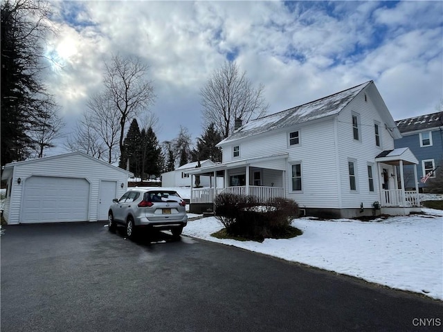 view of snowy exterior with a porch, a garage, and an outbuilding