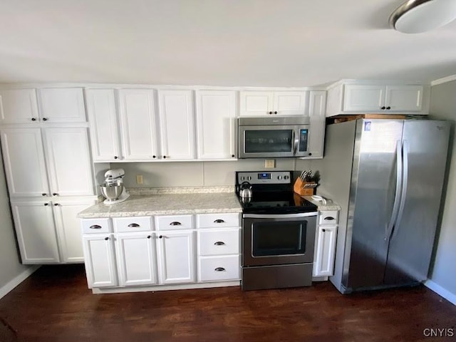 kitchen with light stone countertops, stainless steel appliances, white cabinetry, and dark hardwood / wood-style floors